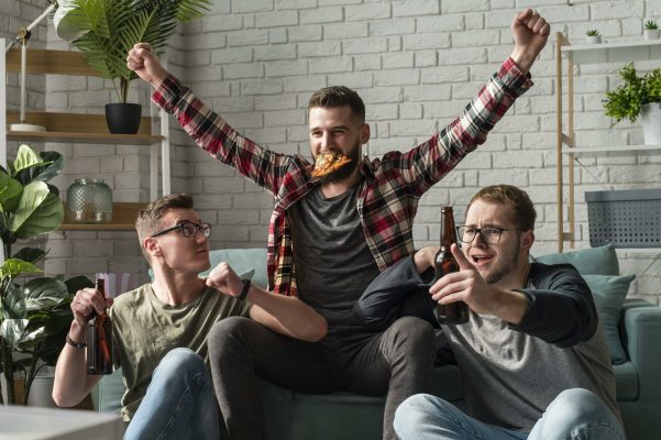 cheerful-male-friends-having-pizza-watching-sports-tv